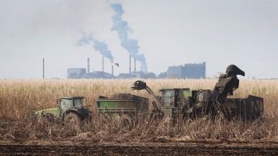 A farm sits before a large smoking factory.